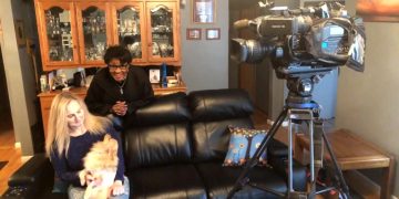 Women and dog seated, filmed by camera crew.