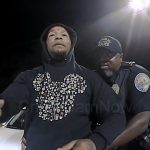 Police officer detaining a person at night.