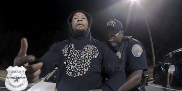 Police officer detaining a person at night.