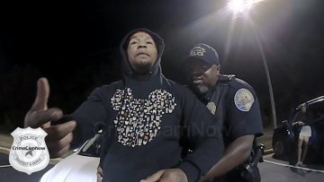 Police officer detaining a person at night.