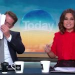 TV hosts on morning show, one reading papers.