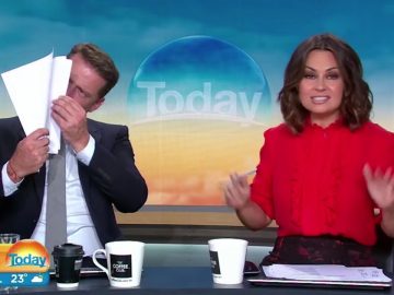 TV hosts on morning show, one reading papers.