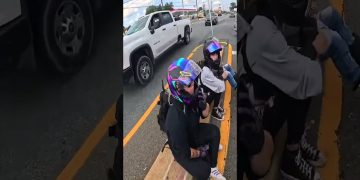 Motorcyclists resting with helmets on road median.