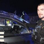 Officer investigates vehicle at night scene.