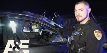 Officer investigates vehicle at night scene.
