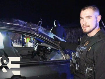 Officer investigates vehicle at night scene.