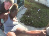 Officer assists woman on sidewalk near car