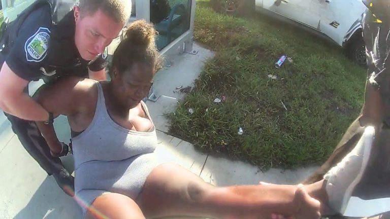 Officer assists woman on sidewalk near car
