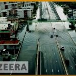 Flooded city road with cars driving through water.