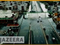 Flooded city road with cars driving through water.