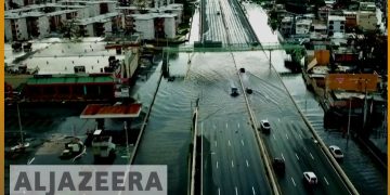 Flooded city road with cars driving through water.