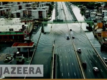 Flooded city road with cars driving through water.