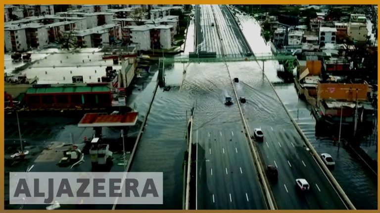 Flooded city road with cars driving through water.