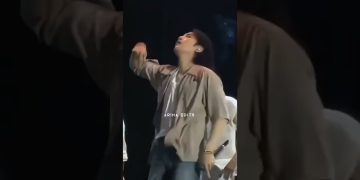 Person performing energetically on stage with microphone.