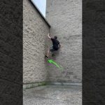 Person climbs brick wall using parkour technique.