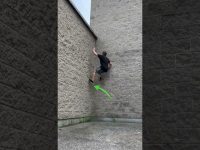 Person climbs brick wall using parkour technique.