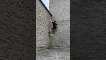 Person climbs brick wall using parkour technique.