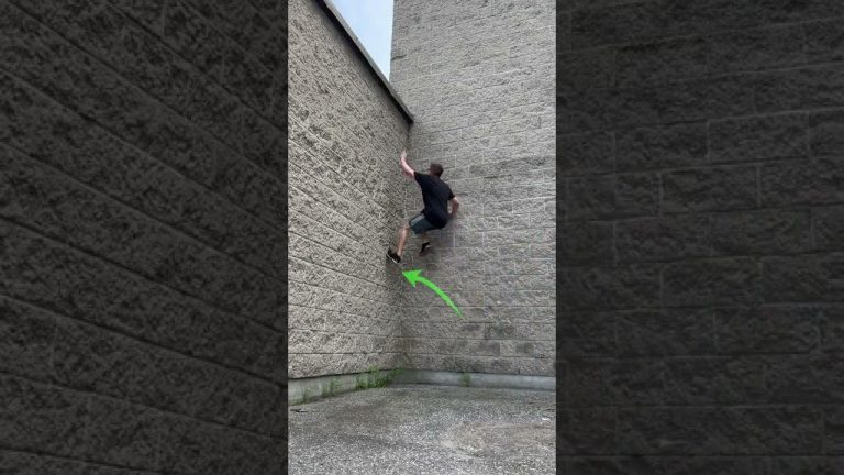 Person climbs brick wall using parkour technique.
