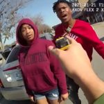 Police interaction with two individuals in parking lot.