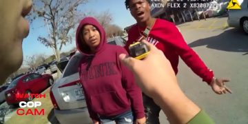 Police interaction with two individuals in parking lot.