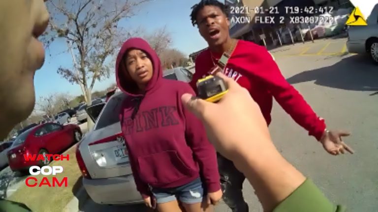 Police interaction with two individuals in parking lot.