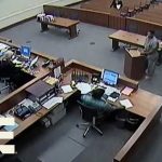 Courtroom scene with officials and a defendant.