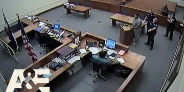 Courtroom scene with officials and a defendant.