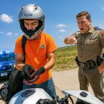 Police officer stops motorcyclist on highway.