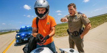 Police officer stops motorcyclist on highway.