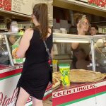 Woman buying pizza at a food counter.