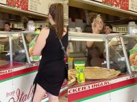 Woman buying pizza at a food counter.