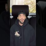 Person smiling in a car with hoodie