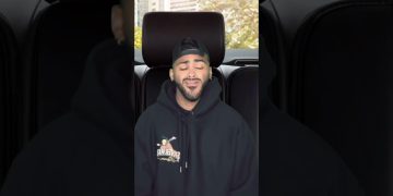 Person smiling in a car with hoodie
