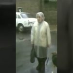 Woman in street near parked white car.