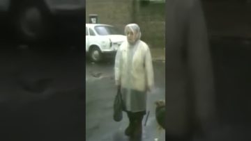 Woman in street near parked white car.