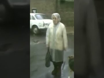Woman in street near parked white car.