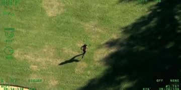 Aerial view of person running on grass.