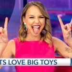 Woman in pink making rock gesture on TV