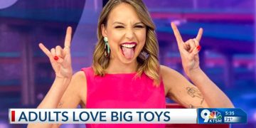 Woman in pink making rock gesture on TV