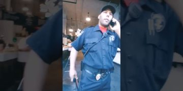 Security officer talking on phone inside building.