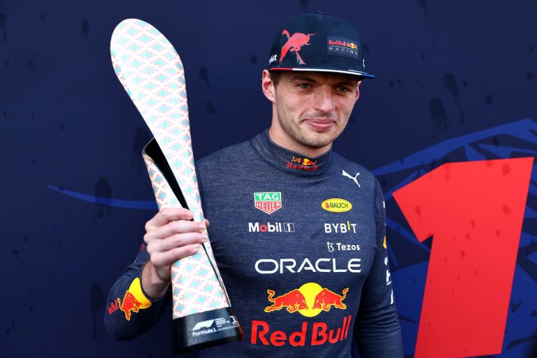 Racing driver holds a unique trophy on podium.
