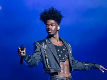 Performer on stage holding microphone, blue background.