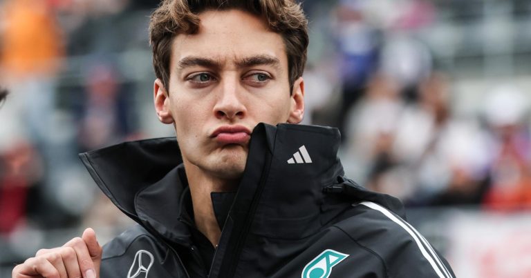 Man in racing jacket pouting at event.