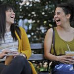 Two women laughing on a park bench.