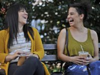 Two women laughing on a park bench.
