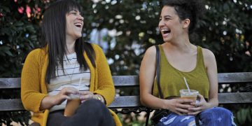 Two women laughing on a park bench.