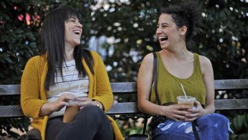 Two women laughing on a park bench.