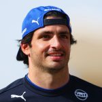 Smiling man wearing a blue cap outdoors.