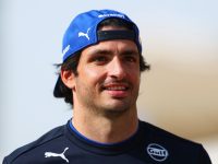 Smiling man wearing a blue cap outdoors.