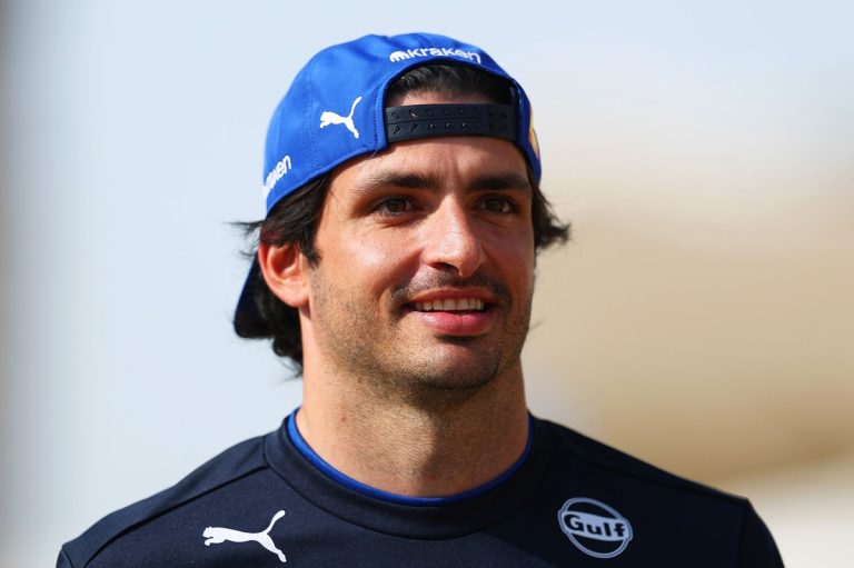 Smiling man wearing a blue cap outdoors.